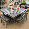 Dining Table set with a table and chairs on a checkered tablecloth, surrounded by other furniture and decor. Homestead Hills 60" Square Table available at Rustic Ranch Furniture and Decor.