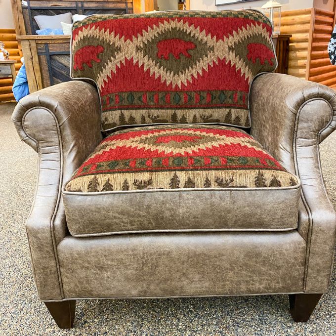 Brown armchair with patterned cushions featuring bears and trees in a store setting. Charles Chair available at Rustic Ranch Furniture and Decor.