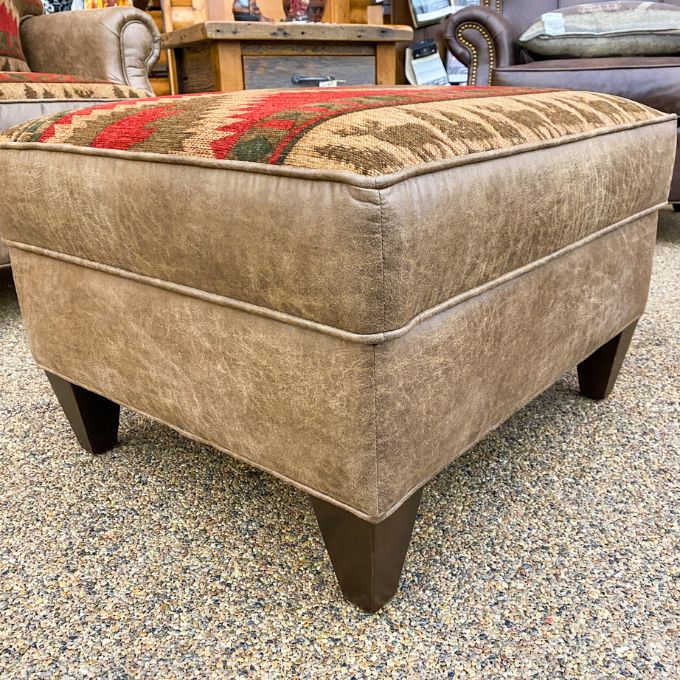 Beige ottoman with patterned top on a concrete floor. Charles Ottoman available at Rustic Ranch Furniture and Decor.