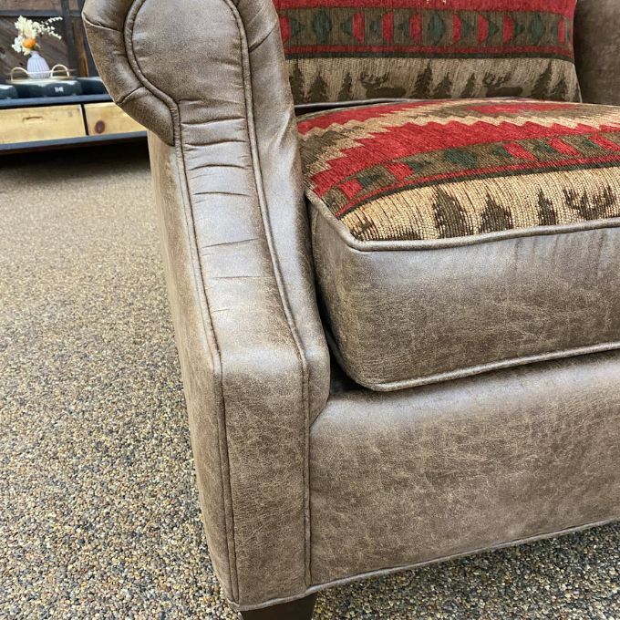 Brown upholstered chair with patterned cushion on a textured floor. Charles Chair available at Rustic Ranch Furniture and Decor.
