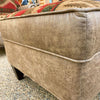 Beige ottoman with a patterned cushion on a speckled floor. Charles Ottoman available at Rustic Ranch Furniture and Decor.