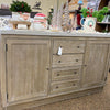 Wooden sideboard with decorative items on a store shelf. Rowan Buffet available at Rustic Ranch Furniture and Decor.