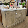 Wooden sideboard with decorative items on a store shelf. Rowan Buffet available at Rustic Ranch Furniture and Decor.
