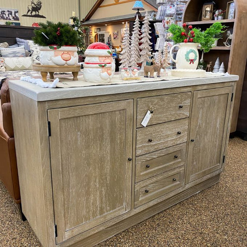 Wooden sideboard with decorative items on a store shelf. Rowan Buffet available at Rustic Ranch Furniture and Decor.