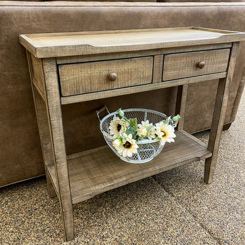Wooden console table with two drawers and a small shelf, featuring a decorative basket of flowers. Beach Pebble Side Table available at Rustic Ranch Furniture and Decor.