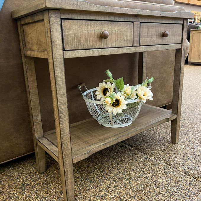 Wooden side table with a wire basket of flowers on a textured surface. Beach Pebble Side Table available at Rustic Ranch Furniture and Decor.