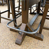 Close-up of a wooden dining table with metal legs on a gravel surface. Homestead Pub Table available at Rustic Ranch Furniture and Decor.