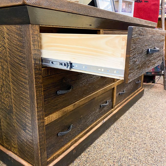 Wooden dresser with open drawer showing metal slide mechanism. Fireside Reclaimed Wood Seven Drawer Dresser available at Rustic Ranch Furniture and Decor.