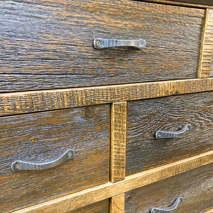 Close-up of a wooden drawer with metal handles. Fireside Reclaimed Wood Seven Drawer Dresser available at Rustic Ranch Furniture and Decor.