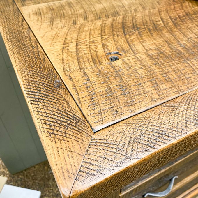 Close-up of a wooden surface with visible grain and texture. Fireside Reclaimed Wood Seven Drawer Dresser available at Rustic Ranch Furniture and Decor.
