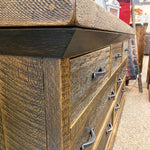 Wooden dresser with metal handles on a street background. Fireside Reclaimed Wood Seven Drawer Dresser available at Rustic Ranch Furniture and Decor.