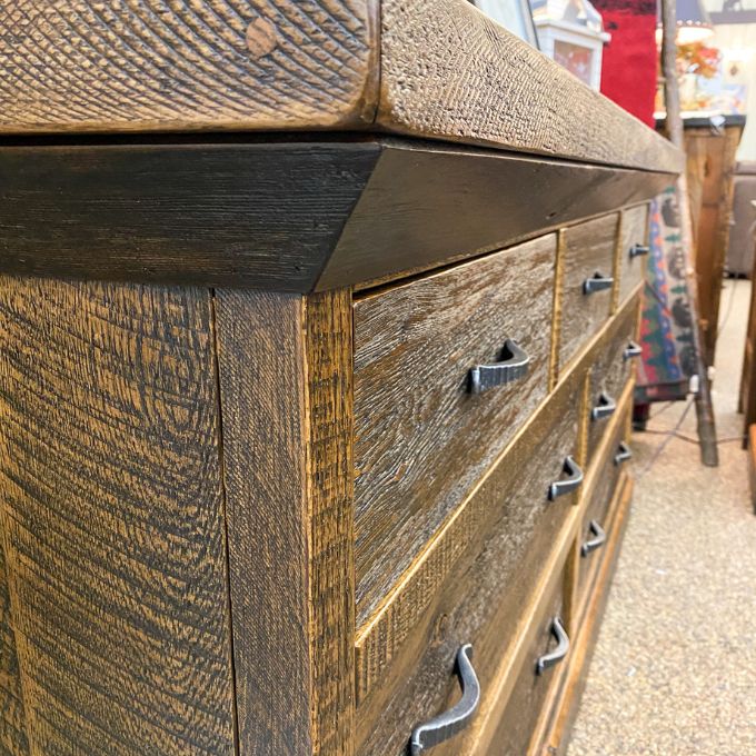 Wooden dresser with metal handles on a street background. Fireside Reclaimed Wood Seven Drawer Dresser available at Rustic Ranch Furniture and Decor.