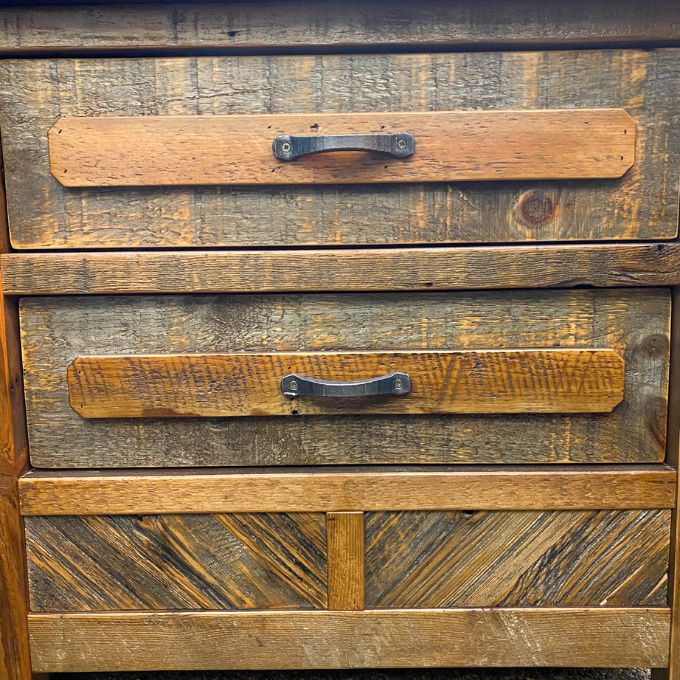 Wooden drawer with two handles on a rustic wooden surface. Jackson Hole Reclaimed Wood Nightstand available at Rustic Ranch Furniture and Decor.