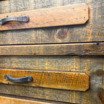 Wooden drawers with metal handles on a rustic wooden surface. Jackson Hole Reclaimed Wood Nightstand available at Rustic Ranch Furniture and Decor.
