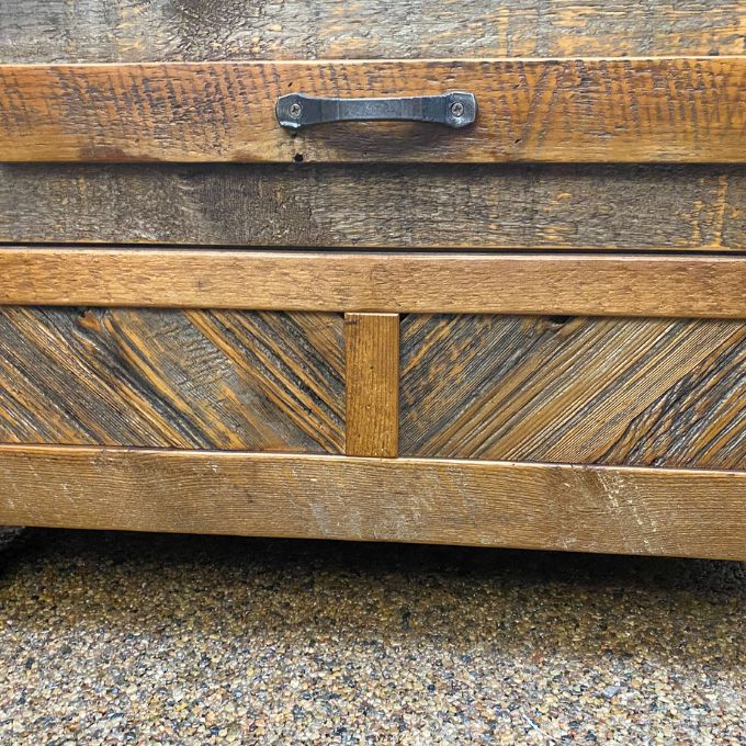 Wooden surface with a metal handle on a textured background. Jackson Hole Reclaimed Wood Nightstand available at Rustic Ranch Furniture and Decor.