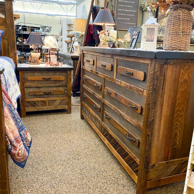 Wooden dresser and nightstand with multiple drawers in a store setting. Jackson Hole Reclaimed Wood Nightstand available at Rustic Ranch Furniture and Decor.