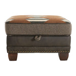 Brown ottoman with patterned top and wooden legs on a white background. Hollister Ottoman available at Rustic Ranch Furniture and Decor.