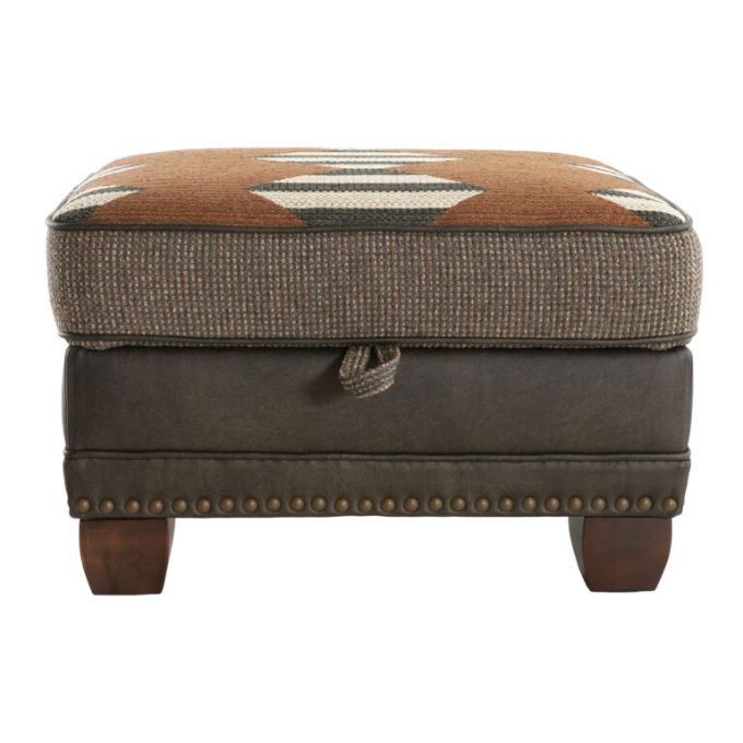 Brown ottoman with patterned top and wooden legs on a white background. Hollister Ottoman available at Rustic Ranch Furniture and Decor.