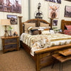 Bedroom with wooden furniture, including a bed and nightstands, with decorative elements like pillows and lamps. Black Hills Two Drawer Nightstand available at Rustic Ranch Furniture and Decor.