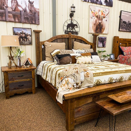 Bedroom with wooden furniture, including a bed and nightstands, with decorative elements like pillows and lamps. Black Hills Two Drawer Nightstand available at Rustic Ranch Furniture and Decor.