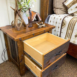 Wooden nightstand with open drawer in a bedroom setting. Black Hills Two Drawer Nightstand available at Rustic Ranch Furniture and Decor.