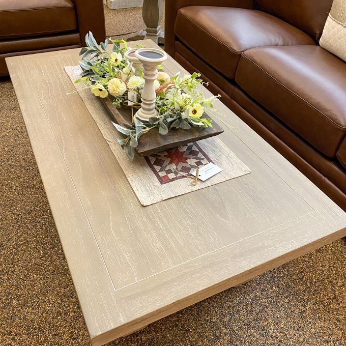 Coffee table with decorative items in a living room setting. Gianna Coffee Table available at Rustic Ranch Furniture and Decor.