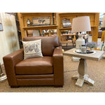 Brown leather armchair and end table with a decorative pillow in a store setting. Gianna End Table available at Rustic Ranch Furniture and Decor.