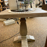 Wooden table with a candle and decorative items on a carpeted floor. Gianna End Table available at Rustic Ranch Furniture and Decor.