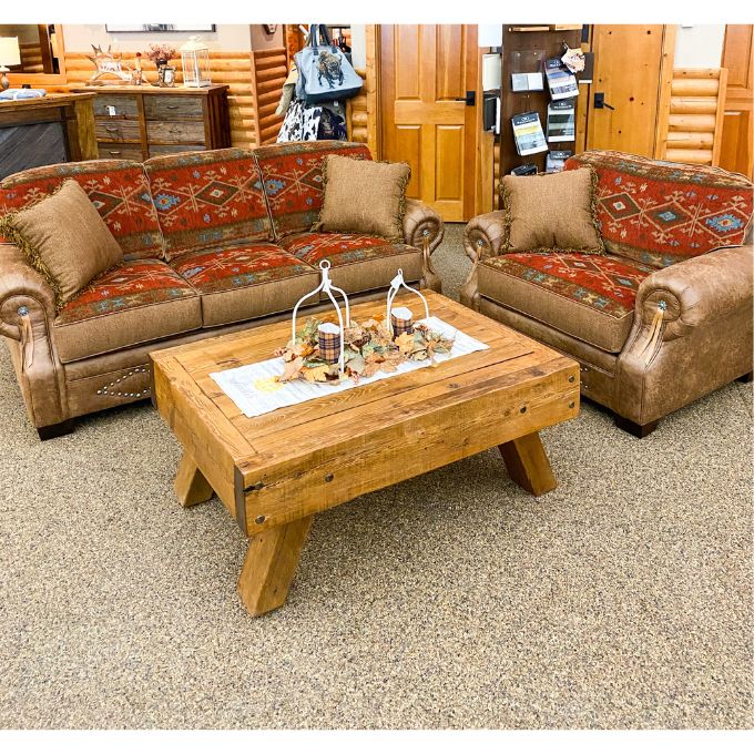 A patterned sofa and a chair with a wooden coffee table in a room with wooden walls.  Emerson Chair and a Half available at Rustic Ranch Furniture and Decor.