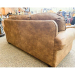Brown leather sofa in a store setting with various items in the background.  Emerson Sofa available at Rustic Ranch Furniture and Decor.