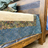 Close-up of a wooden bed with a quilt draped over it.  Fireside bed available at Rustic Ranch Furniture and Decor.