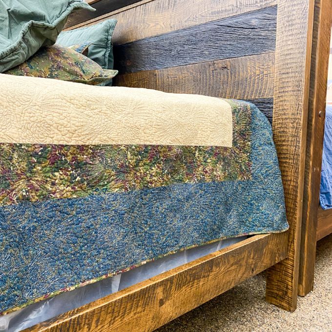 Close-up of a wooden bed with a quilt draped over it.  Fireside bed available at Rustic Ranch Furniture and Decor.