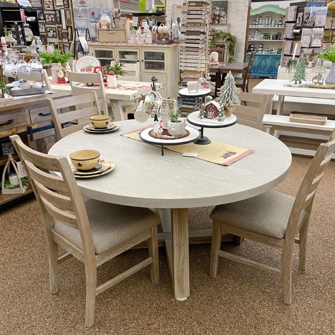 Round dining table with chairs in a store setting. Rowan Round Dining Table available at Rustic Ranch Furniture and Decor.