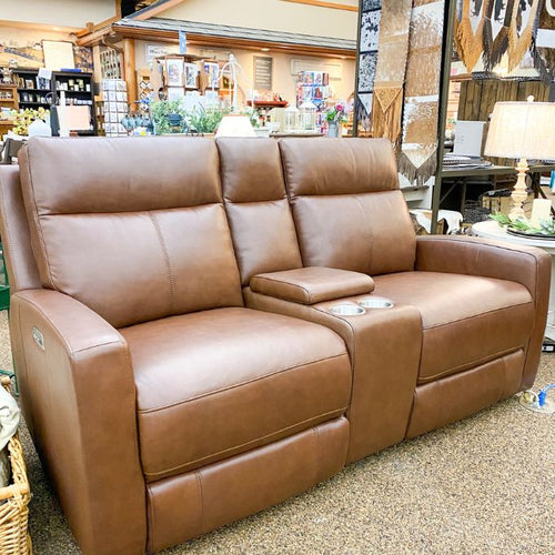 Brown leather love seat in a store setting with various items in the background.  Vienna Reclining Love Seat available at Rustic Ranch Furniture and Decor.