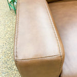 Close-up of a brown leather seat with visible stitching on a textured surface.  Vienna Reclining Love Seat available at Rustic Ranch Furniture and Decor.