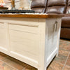 Wooden storage chest with a brown top in a living room setting. White Dashbury Storage Trunk available at Rustic Ranch Furniture and Decor.