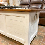 Wooden storage chest with a brown top in a living room setting. White Dashbury Storage Trunk available at Rustic Ranch Furniture and Decor.