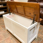 Wooden storage chest with a white interior in a living room setting. White Dashbury Storage Trunk available at Rustic Ranch Furniture and Decor.