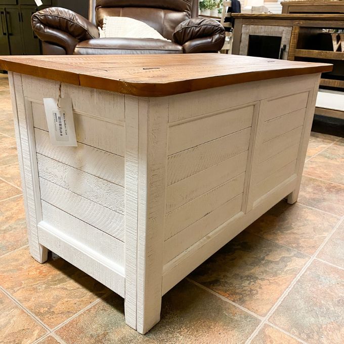 Wooden storage chest with a wooden top on a tiled floor. White Dashbury Storage Trunk available at Rustic Ranch Furniture and Decor.