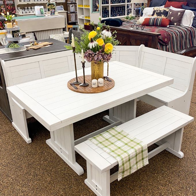 White breakfast nook table with bench and decorative items in a store setting. Bayside Nook available at Rustic Ranch Furniture and Decor.