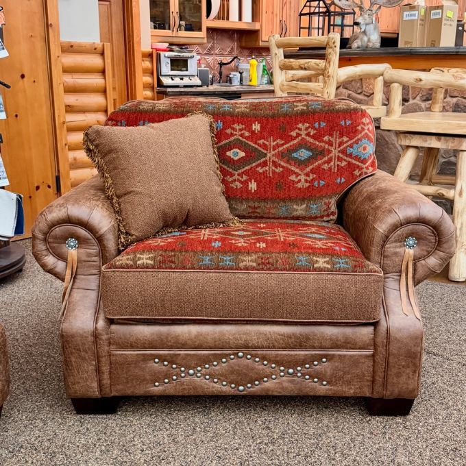 Brown leather armchair with decorative patterns in a rustic setting. Emerson Chair and a Half available at Rustic Ranch Furniture and Decor.