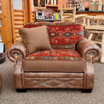 Brown leather armchair with decorative patterns in a rustic setting. Emerson Chair and a Half available at Rustic Ranch Furniture and Decor.