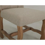 Chair with beige cushioned seat and wooden frame on a white background. Marquez Dining chair available at Rustic Ranch Furniture and Decor.