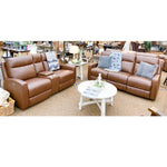 Two brown leather reclining sofas in a showroom setting with a small table and decorative items.  Vienna Reclining Love Seat and Sofa available at Rustic Ranch Furniture and Decor.